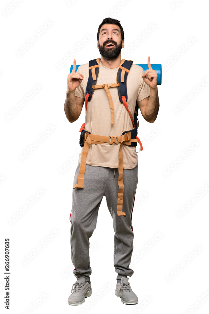 Hiker man surprised and pointing up over isolated white background Hiker man surprised and pointing up over isolated white background