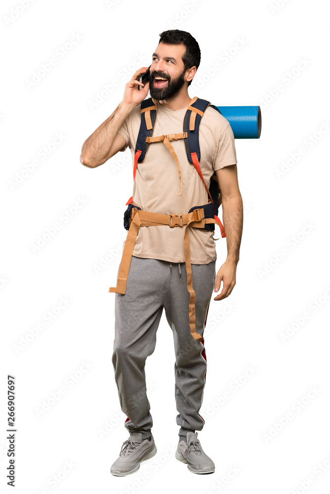 Hiker man keeping a conversation with the mobile phone over isolated white background Hiker man keeping a conversation with the mobile phone over isolated white background