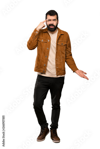 Handsome man with beard making the gesture of madness putting finger on the head over isolated white background © luismolinero