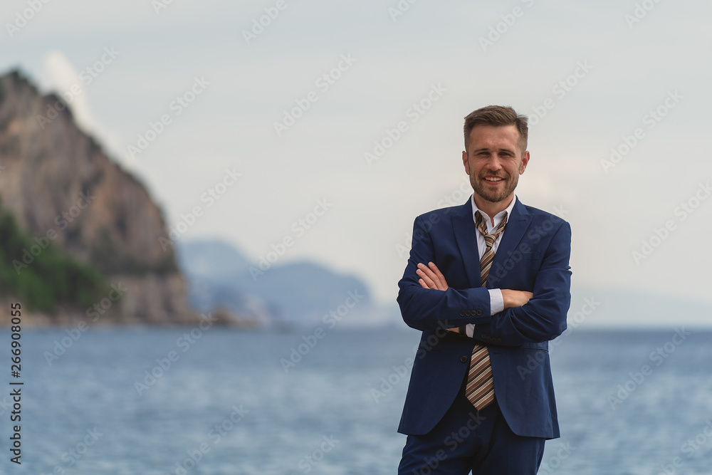 Businessman standing on the beach in a suit a untied tie. He looks at the camera and laughs, he is happy Businessman standing on the beach in a suit a untied tie. He looks at the camera and laughs, he is happy