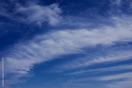 A deep blue sky with light white clouds background