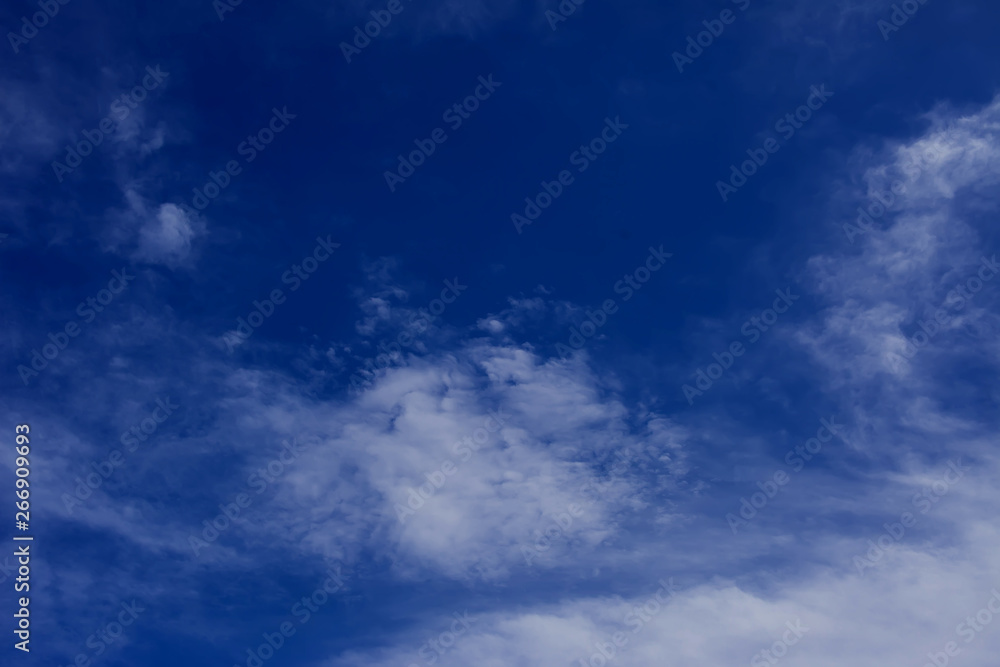 A deep blue sky with light white clouds background