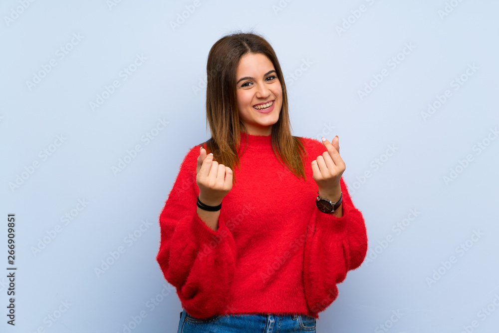 Young woman over isolated blue wall making money gesture Young woman over isolated blue wall making money gesture