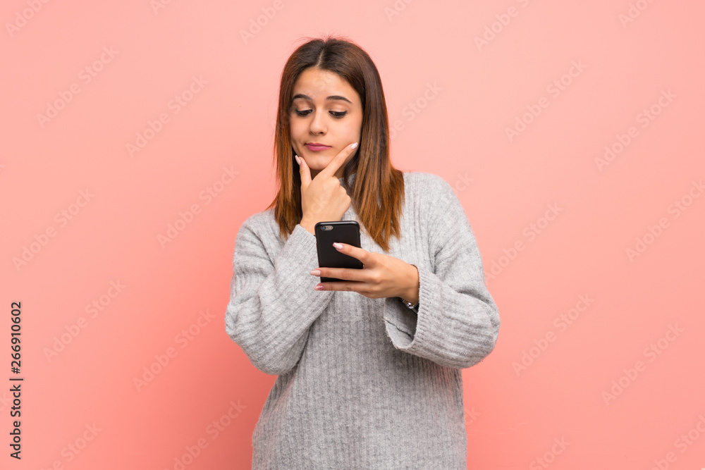 Young woman over pink wall thinking and sending a message Young woman over pink wall thinking and sending a message