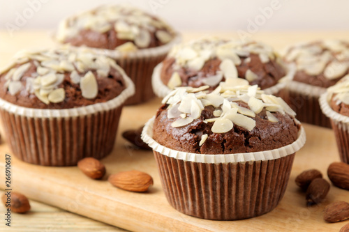 Delicious, sweet chocolate muffins, with almond petals next to almond nuts on a natural wooden table. close-up