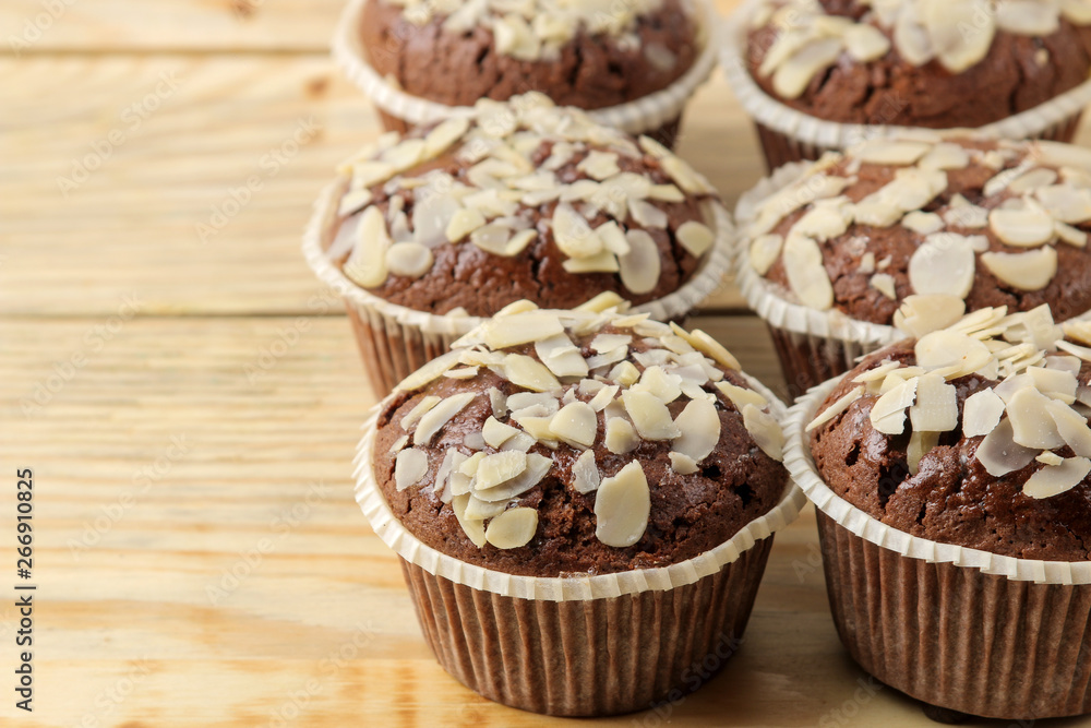 Delicious, sweet chocolate muffins, with almond petals next to almond nuts on a natural wooden table. close-up