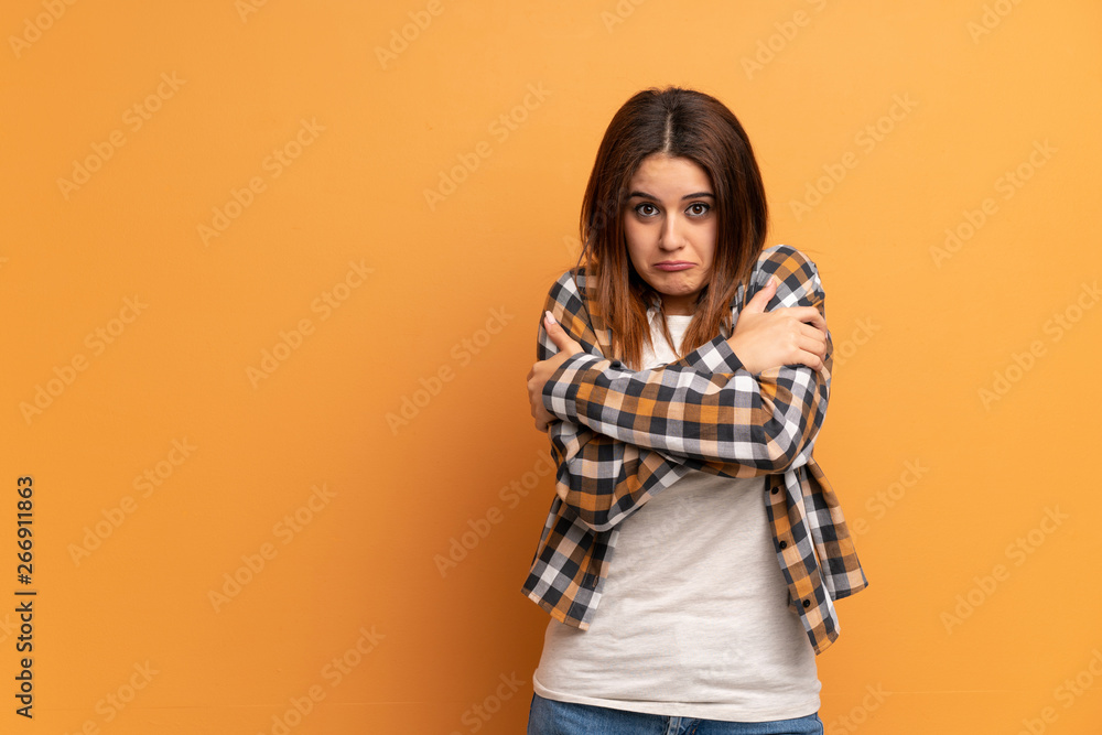 Young woman over brown wall freezing Young woman over brown wall freezing