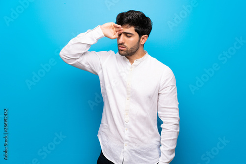 Young man over isolated blue wall with tired and sick expression