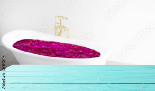Bathed in flower bath ritual. Blue wooden shelf on bathroom background. Wood desk table with top view and copy space white bath at hotel. Room service and shower spa concept. Selective focus. Banner