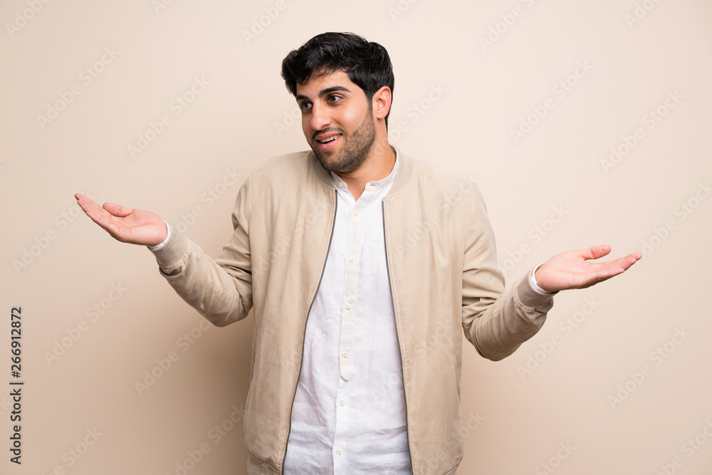 Young man over isolated wall holding copyspace with two hands
