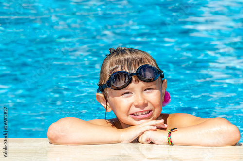 Pretty little girl bathes in the pool on a Sunny day.