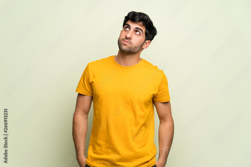 Young man over pink wall looking up with serious face Young man over pink wall looking up with serious face