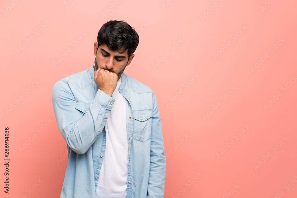 Young man over pink wall having doubts Young man over pink wall having doubts