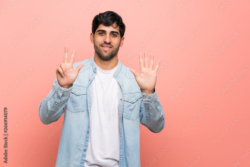 Naklejka premium Young man over pink wall counting eight with fingers