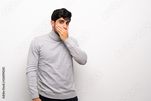 Young man over isolated white wall covering mouth with hands © luismolinero