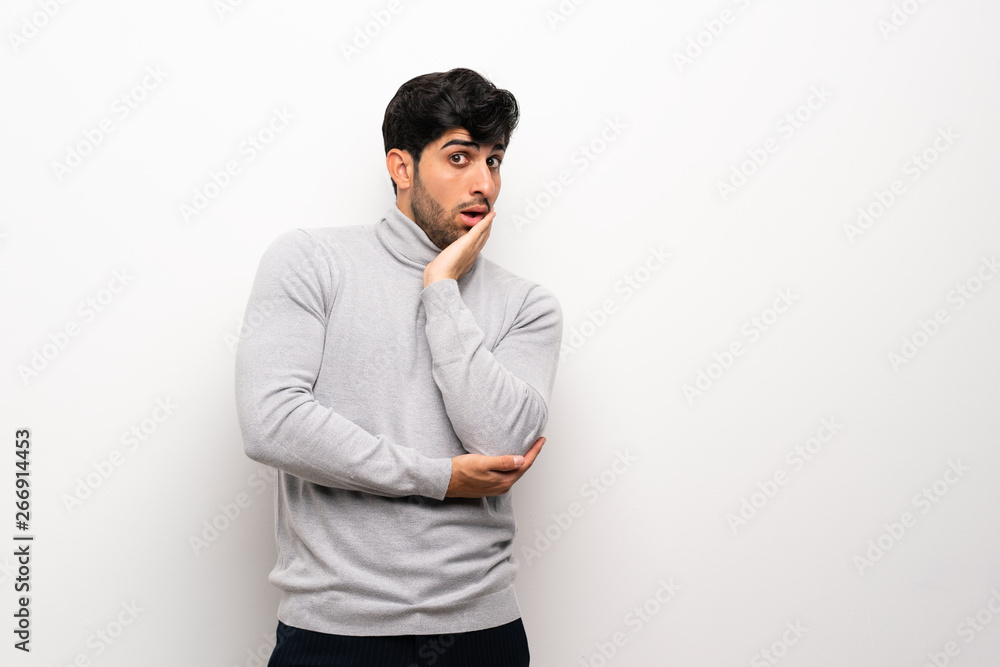 Young man over isolated white wall surprised and shocked while looking right Young man over isolated white wall surprised and shocked while looking right