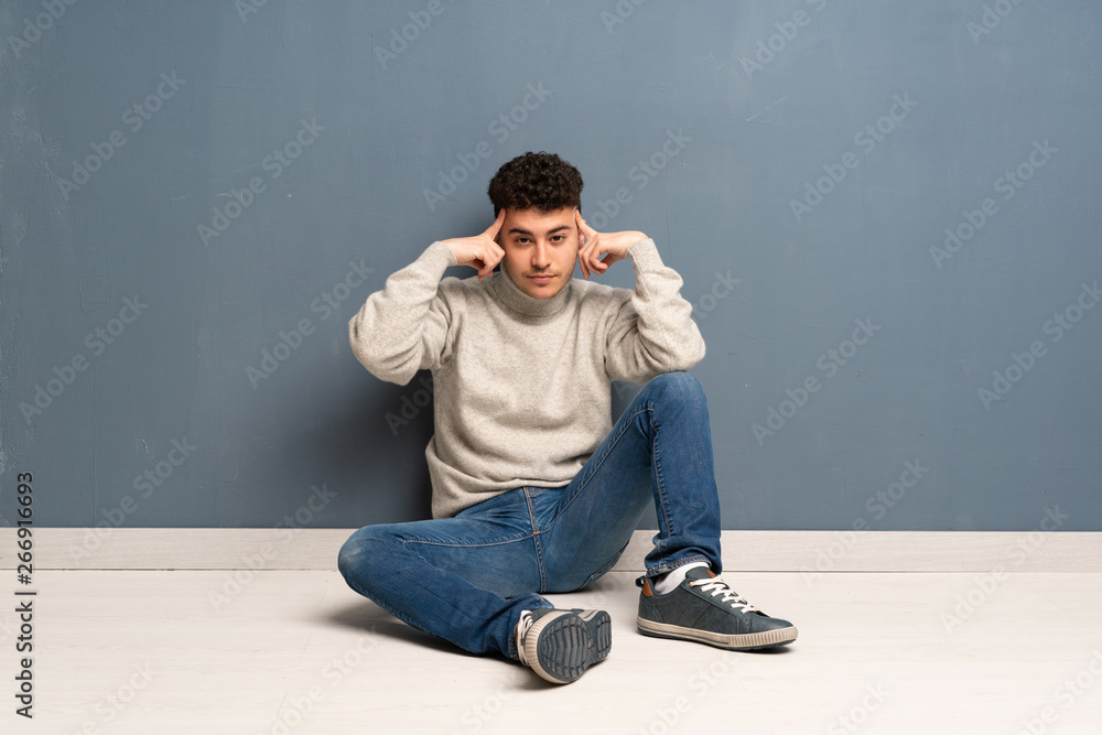 Young man sitting on the floor having doubts and thinking Young man sitting on the floor having doubts and thinking