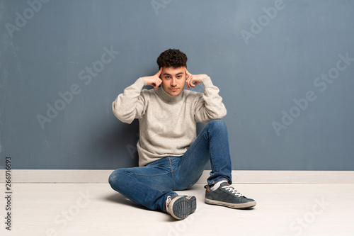 Young man sitting on the floor having doubts and thinking