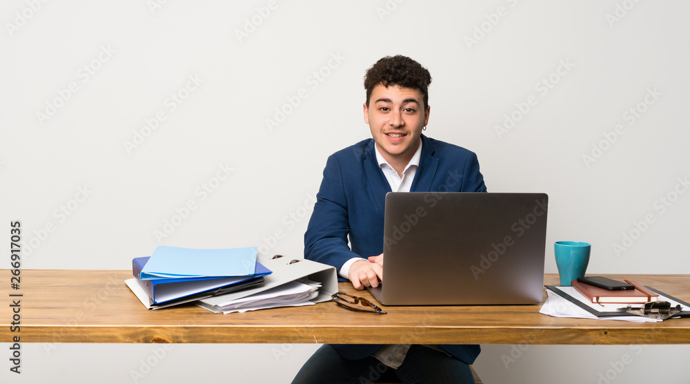 Business man in a office posing with arms at hip and smiling Business man in a office posing with arms at hip and smiling