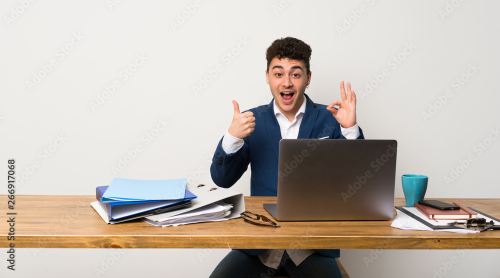 Business man in a office showing ok sign and thumb up gesture Business man in a office showing ok sign and thumb up gesture