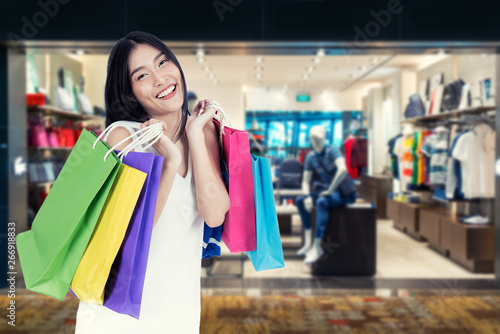 Beautiful Asian woman with shopping bags in clothes shop. Sale, shopping, tourism and happy people concept