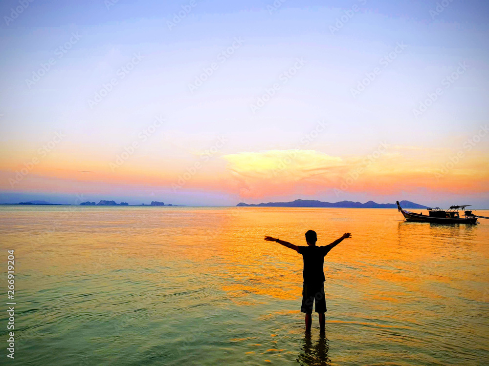 happy fresh morning sunrise with amazing luxury horizon , beautiful color of sea and young man slowly exercising for good health, near fishing boat at Koh Kradan Island, South of Thailand.Andaman