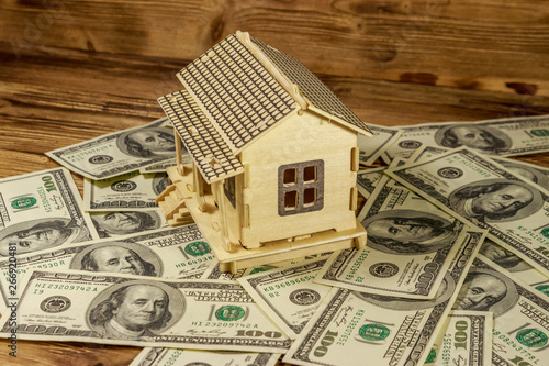 House model and U.S. one hundred dollar bills on wooden background. Property investment, home loan, house mortgage, real estate concept photo