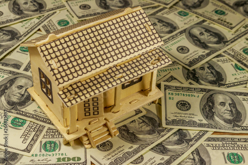 House model on background of U.S. one hundred dollar bills. Property investment, home loan, house mortgage, real estate concept photo