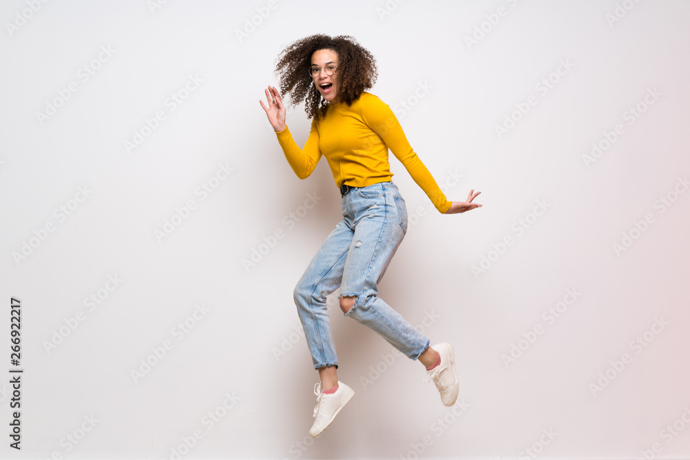 Dominican woman with curly hair jumping over isolated white background Dominican woman with curly hair jumping over isolated white background