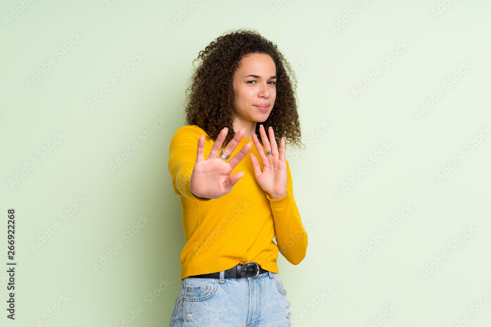 Dominican woman over isolated green background nervous stretching hands to the front Dominican woman over isolated green background nervous stretching hands to the front