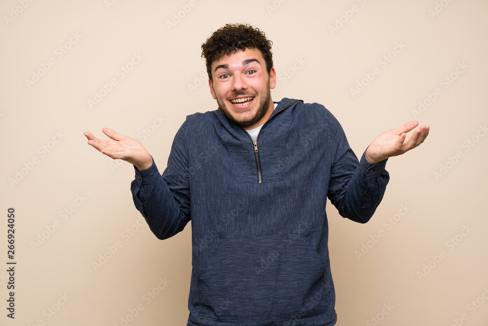 Man with curly hair over isolated wall with shocked facial expression Man with curly hair over isolated wall with shocked facial expression