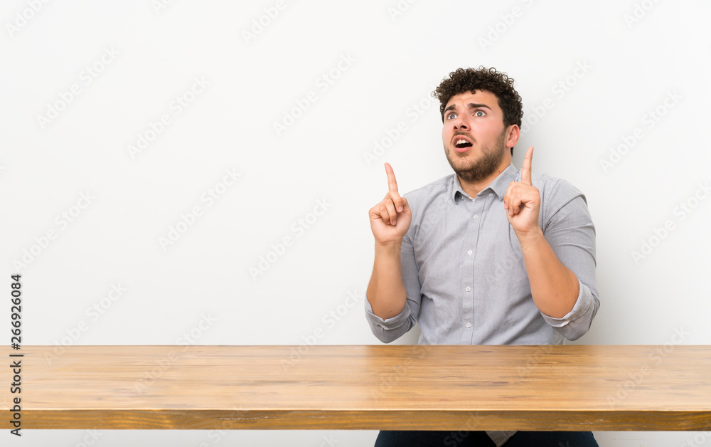 Young man with a table surprised and pointing up Young man with a table surprised and pointing up