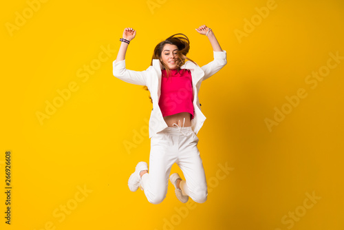 Young woman jumping over isolated yellow wall