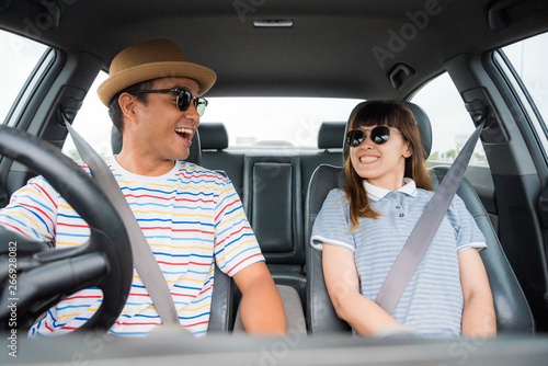 Front view of Funny moment couple asian man and woman sitting in car. Enjoying travel concept. © Nopphon