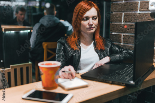 Businesswoman, girl working on laptop in cafe, smartphone, pen, use computer. Freelancer works remotely. Online marketing, education for adulte. Night city, dark theme.