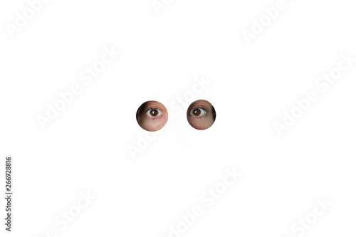 Eyes peering through holes in white wall photo