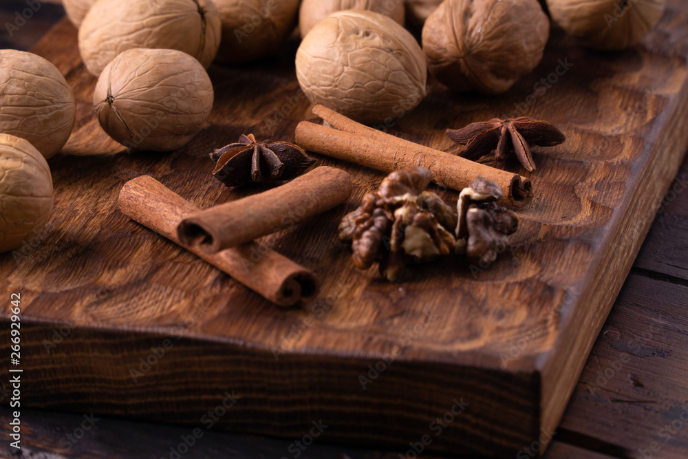 Walnuts, cinnamon and star anise on wooden cutting board. Nuts and spices on the table. Food composition close-up.