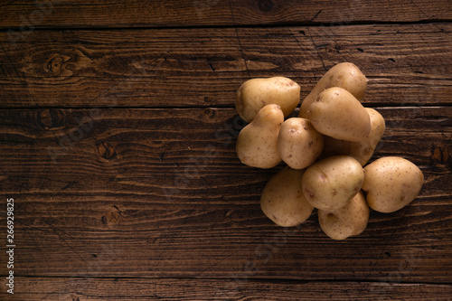 Heap of fresh clean potatoes on rustic wooden surface. Organic food, carbs, tubers.