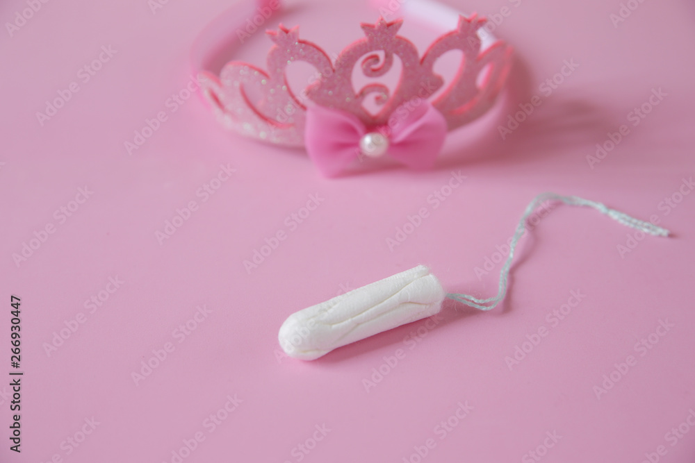 Clean white cotton tampons on pink background with a crown in the background in soft blur. Menstruation. Feminine Hygiene in periods, beauty treatment. Clean white cotton tampons on pink background with a crown in the background in soft blur. Menstruation. Feminine Hygiene in periods, beauty treatment.