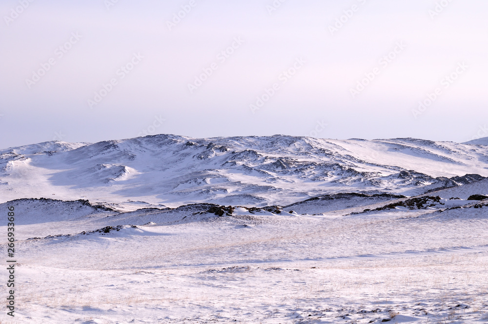 Early morning sunrise in Tazheran steppes. Snow-covered hills are colored in shades of ultra-violet. Photo toned.