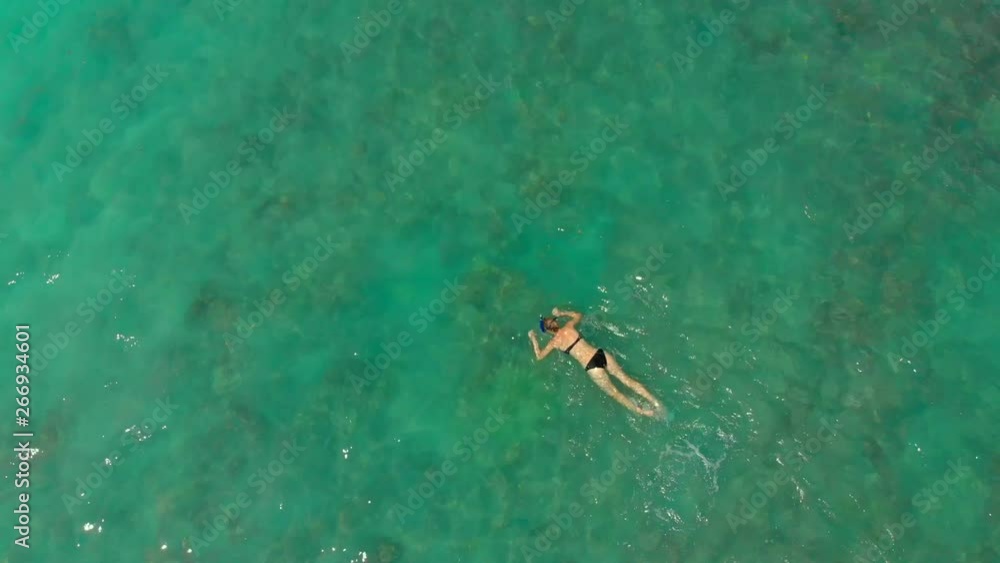 Aerial shot of a young woman snorkeling in an open sea watching corals and exotic fishes Aerial shot of a young woman snorkeling in an open sea watching corals and exotic fishes