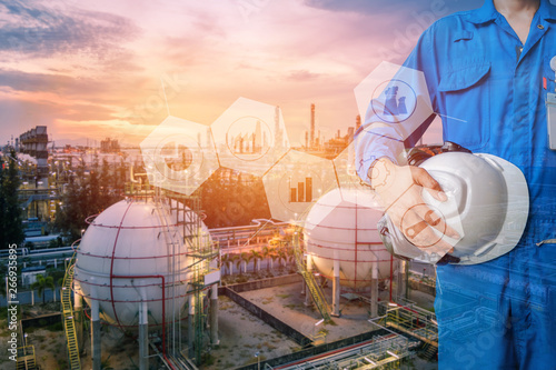 Engineer working in petroleum industrial concept,Technician stand hand holding safety helmet with blue uniform on petrochemical industrial background, Double exposure