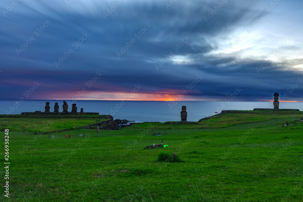 Long exposure of Moais in the Ahu Tahai at sunset against deep cloudy sky