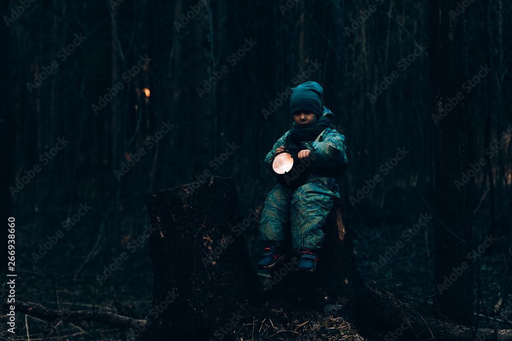 little baby alone in the dark forest with a flashlight