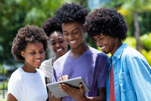 Group of african american young adults watching movie with digital tablet