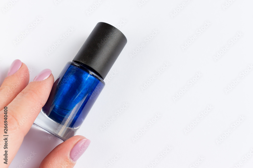 Woman hand with blue nail polish bottle on white background. Copyspace Woman hand with blue nail polish bottle on white background. Copyspace