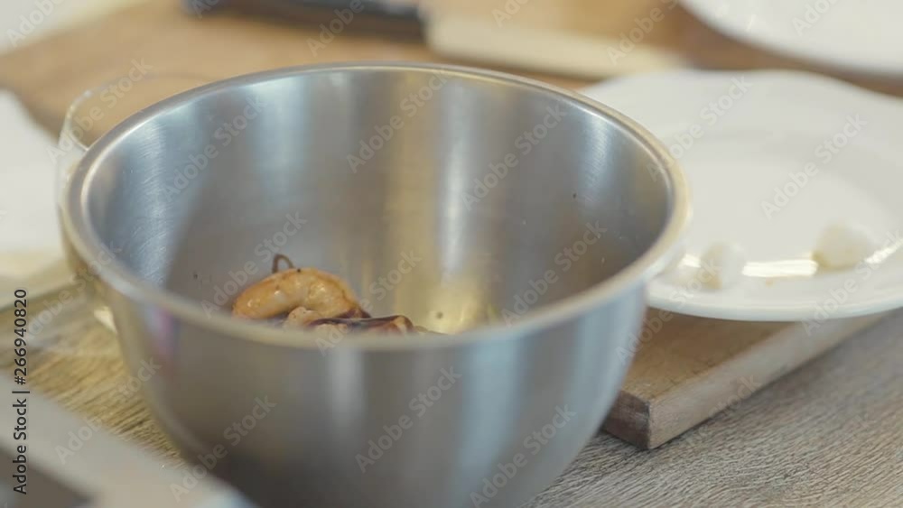 King shrimps in the small metal bowl pouring with the sauce close up. Chef's hand pouring the dish with dressing. Seafood preparation King shrimps in the small metal bowl pouring with the sauce close up. Chef's hand pouring the dish with dressing. Seafood preparation