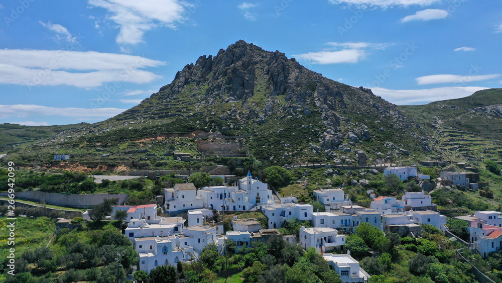 Aerial drone photo of picturesque traditional village of Koumaros in the slopes of mountain and castle of Exomvourgo or Exombourgo with beautiful deep blue sky, Tinos island, Cyclades, Greece