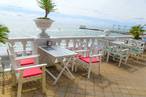 tables and chairs on  terrace of beach restaurant on the embankment on a sunny day