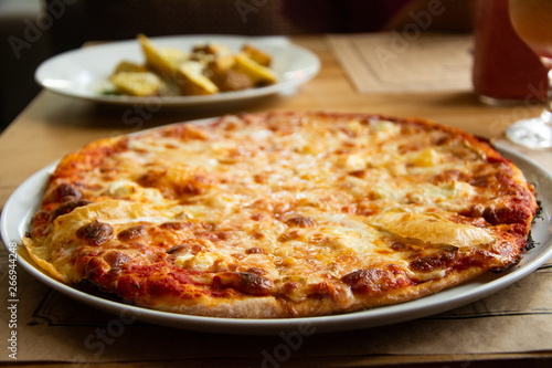 Big cheese pizza on the table in the restaurant.
